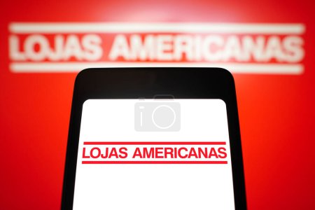Foto de 28 de febrero de 2024, Brasil. En esta ilustración fotográfica, el logotipo de Lojas Americanas se muestra en la pantalla de un smartphone y en el fondo - Imagen libre de derechos