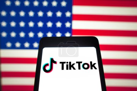 Photo for March 12, 2024, Brazil. In this photo illustration, the TikTok logo is displayed on a smartphone screen and in the background, the flag of the United States of America (US) - Royalty Free Image