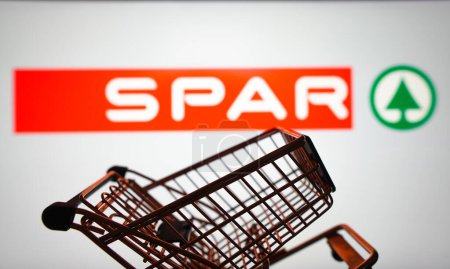Photo for March 31, 2024, Brazil. In this photo illustration, the SPAR logo seen displayed on a smartphone along with a shopping cart - Royalty Free Image