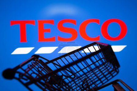 Photo for March 31, 2024, Brazil. In this photo illustration, the Tesco logo seen displayed on a smartphone along with a shopping cart - Royalty Free Image