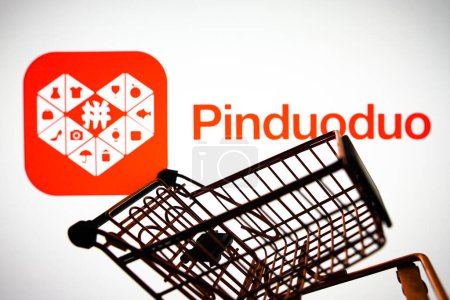 Foto de 5 de abril de 2024, Brasil. En esta ilustración fotográfica, el logotipo de Pinduoduo se muestra en un teléfono inteligente junto con un carrito de compras - Imagen libre de derechos