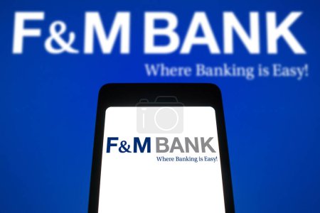 Foto de 9 de abril de 2024, Brasil. En esta ilustración fotográfica, el logotipo de F & M Bank se muestra en la pantalla de un teléfono inteligente y en el fondo - Imagen libre de derechos