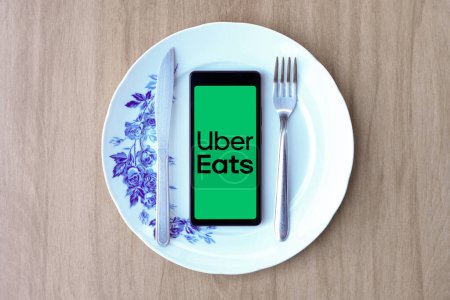 Photo for April 29, 2024, Brazil. In this photo illustration, the Uber Eats logo is displayed on a smartphone screen inside a plate with cutlery - Royalty Free Image