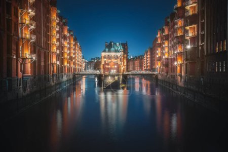 Foto de Famosa vista del distrito de almacenes de Speicherstadt con el edificio Wasserschloss por la noche - Hamburgo, Alemania - Imagen libre de derechos