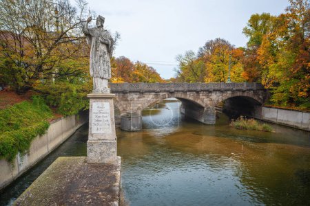 Foto de Múnich, Alemania - 03-nov-2019: Estatua de Juan de Nepomuk y Puente de Prjalá (Praterwehrbrucke) - Múnich, Baviera, Alemania - Imagen libre de derechos