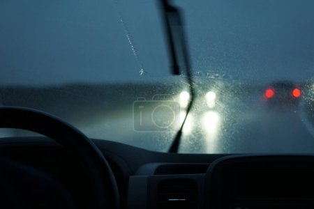 Photo for Driving a car in the rain with activated windshield wipers - Royalty Free Image