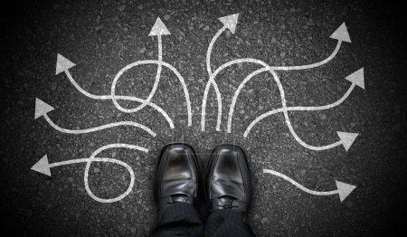 Black business shoes and many winding chalky arrows on asphalt - decision concept