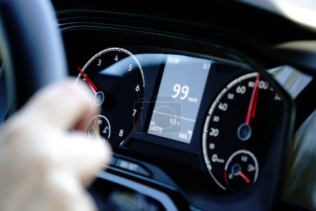 Speedometer and hands on a steering wheel - driving at 99 kmh
