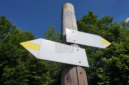 Wooden signpost with two white and yellow arrows