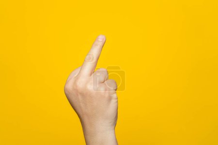 Téléchargez les photos : Finger hand symbols concept isolated sign of the middle finger in a gesture meaning fuck you or fuck off on yellow background - en image libre de droit