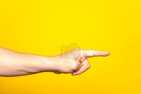 Foto de Mano de hombre apuntando a algo con el dedo índice, aislado sobre fondo amarillo. Un gesto de elección. Vista lateral. - Imagen libre de derechos