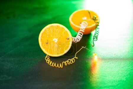 Photo for Free energy electricity generator using oranges in green light. - Royalty Free Image