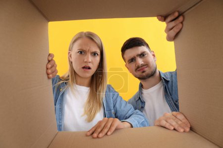 Concepto de entrega, joven hombre y mujer mirar en la caja