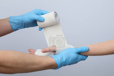 Téléchargez les photos : Concept de blessure à la main aide avec un bandage élastique - en image libre de droit