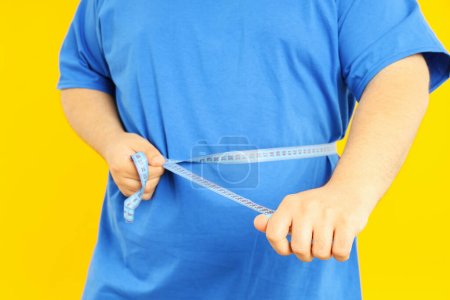Photo for Concept of weight problems, young fat man on yellow background - Royalty Free Image