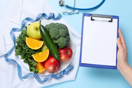 Téléchargez les photos : Aliments sains et accessoires pour médecins sur fond bleu - perte de poids - en image libre de droit
