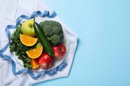 Téléchargez les photos : Manteau des médecins, aliments sains et ruban à mesurer sur fond bleu - perte de poids - en image libre de droit