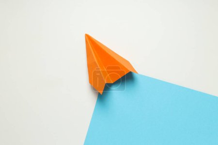 Photo for Orange paper plane on white - blue background - Royalty Free Image