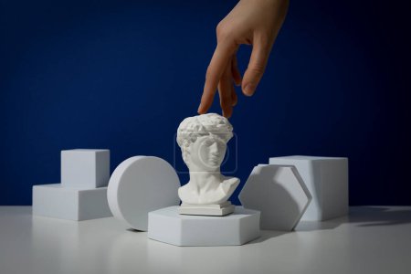 Estatua de yeso de la cabeza de David con figuras gnométricas y una mano