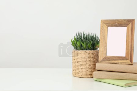 A photo frame on a table with a houseplant and books