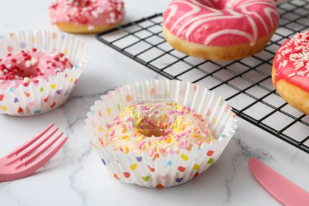 Photo for Glazed donuts on grid and in paper cupcake cups on marble background - Royalty Free Image