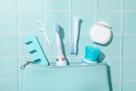 Téléchargez les photos : Brosse à dents électrique et sac cosmétique sur fond bleu, vue de dessus - en image libre de droit