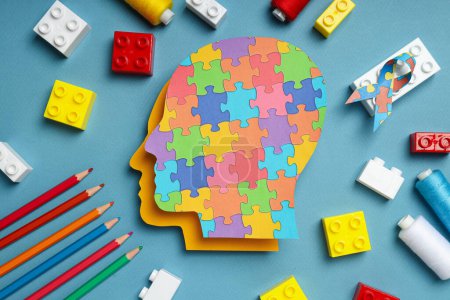 Paper human heads with colorful puzzle pieces on a light background. World autism day concept