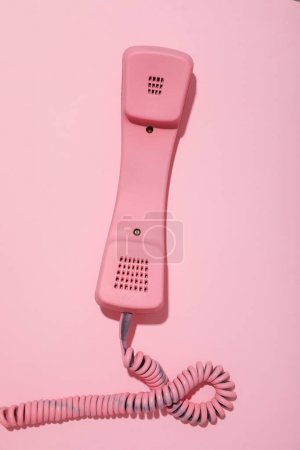 Vintage pink phone on pink background, top view