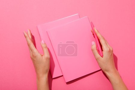 Photo for Notebooks, pen and female hands on pink background, top view - Royalty Free Image