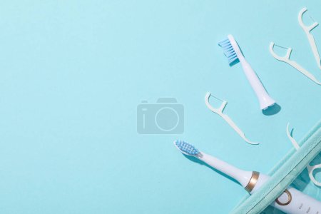 Téléchargez les photos : Brosses à dents électriques et fil dentaire sur fond bleu, espace pour le texte - en image libre de droit