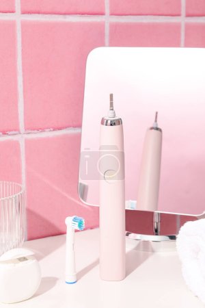 Téléchargez les photos : Brosse à dents électrique et miroir sur table sur fond rose - en image libre de droit