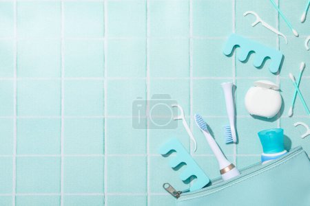 Téléchargez les photos : Brosse à dents électrique et sac cosmétique sur fond bleu, espace pour le texte - en image libre de droit