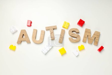 The word "autism" in wooden letters on a light background with legos. World autism day concept