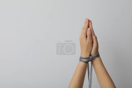 Téléchargez les photos : Mains liées par un ruban sur un fond clair. - en image libre de droit