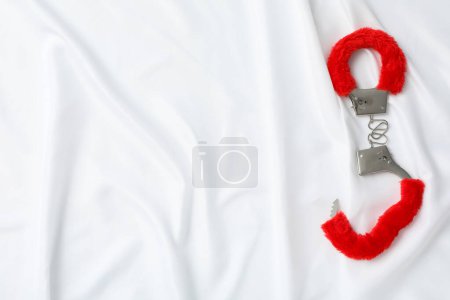 Téléchargez les photos : Rouge, menottes moelleuses pour le jeu sexuel sur un fond blanc. - en image libre de droit