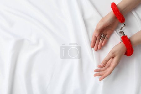 Téléchargez les photos : Rouge, menottes moelleuses pour le jeu sexuel sur un fond blanc. - en image libre de droit