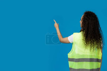 Photo for A girl in noise-absorbing headphones and a folder on a blue background - Royalty Free Image