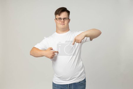 Photo for A smiling young man with cerebral palsy in glasses and a white T-shirt poses for the camera. World Genetic Diseases Day concept - Royalty Free Image
