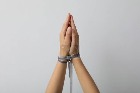 Téléchargez les photos : Mains liées par un ruban sur un fond clair. - en image libre de droit