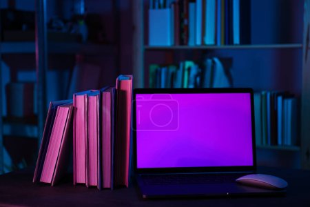 Photo for Laptop and stack of books on dark background - Royalty Free Image