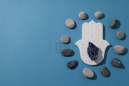 Photo for Hamsa, stones and natural stone on blue background, space for text - Royalty Free Image