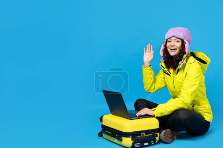 Foto de Una chica en un traje de esquí con una maleta y un portátil. - Imagen libre de derechos