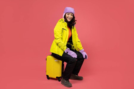 Foto de Una mujer en un cálido traje de esquí con una maleta. - Imagen libre de derechos
