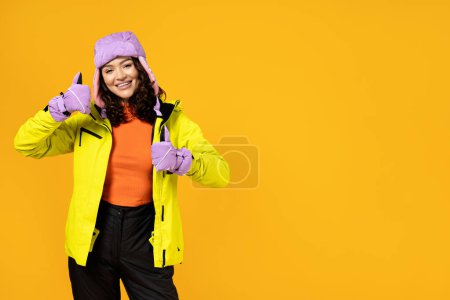 Foto de Una mujer en un cálido traje de esquí sobre un fondo amarillo. - Imagen libre de derechos