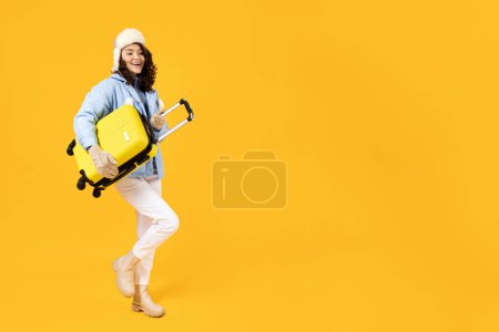 Foto de Una mujer en un cálido traje de esquí con una maleta. - Imagen libre de derechos