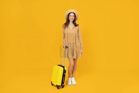 Foto de Chica joven con una maleta sobre un fondo amarillo. - Imagen libre de derechos