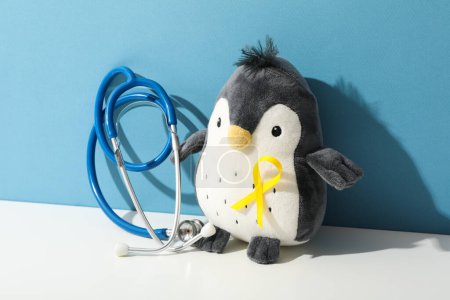 Téléchargez les photos : Un stéthoscope avec un pingouin jouet et un ruban jaune - en image libre de droit