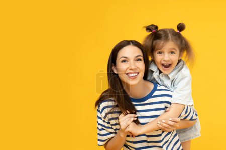 Téléchargez les photos : Mère et fille posent pour une photo sur un fond jaune. - en image libre de droit