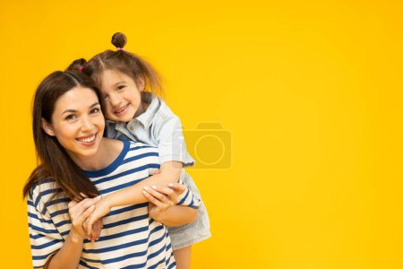Téléchargez les photos : Mère et fille jouent, sur fond jaune. - en image libre de droit
