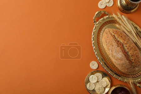 Bread on golden tray and spikelets on orange background, space for text